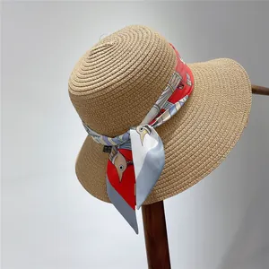 Close-up of a woven straw sun hat detailed with a colorful printed silk scarf ribbon