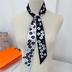 Détail d'un foulard étroit en soie avec imprimé marguerites et lettres sur mannequin