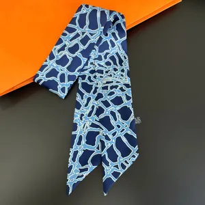 Detail van donkerblauwe zijdeachtige twilly sjaal met lichtblauw patroon op oranje achtergrond
