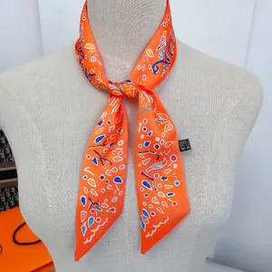 Close-up of an orange printed narrow silk twilly tied on a mannequin neck with abstract patterns