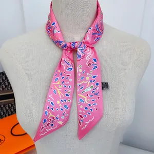 Close-up of pink satin skinny scarf with abstract geometric patterns on a mannequin