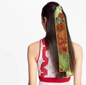 Artistic floral silk twilly scarf styled as an elegant hair ribbon on female model