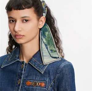 Gros plan du foulard en soie imprimé vert noué dans les cheveux et veste en jean