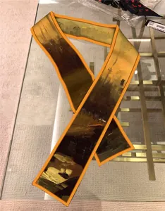 Detailed view of an orange-edged silk bandeau scarf with abstract oil painting texture