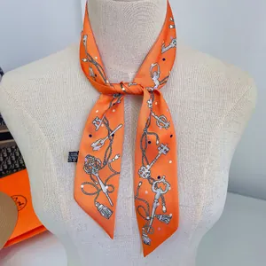 Close-up of orange printed polyester scarf with vintage key patterns on a neck model