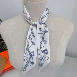 Detail of a white silk twilly scarf with blue vintage key patterns tied on a mannequin
