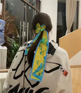 Foulard per capelli in seta gialla con trame blu e verdi legato a una coda di cavallo