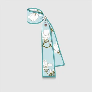 Dettaglio foulard in seta azzurra con fiori di magnolia e calligrafia in stile cinese