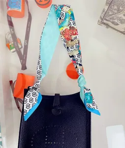 Detail of silk twilly scarf with abstract patterns wrapped on black leather bag handle