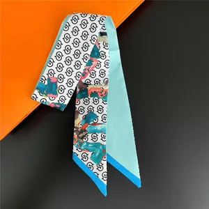 Detail shot of a slim silk scarf featuring elegant blue base with stylish letter prints