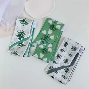 Close-up van drie elegante twilly zijden sjaals met bloemenprint en parelaccenten