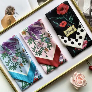 Close-up of floral print satin hair scarves in light blue, pink and black dot designs