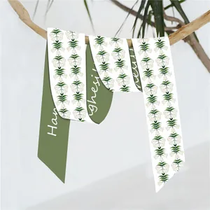 Detail van dubbelzijdige zijden sjaal met meiklokjesmotief en olijfgroene tekstprint