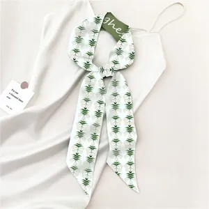 Detail van zijden sjaal met groene lelietje-van-dalen print op witte jurk