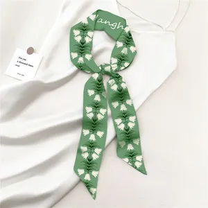 Detail van een groene zijden sjaal met witte lelietje-van-dalen bloemenpatronen