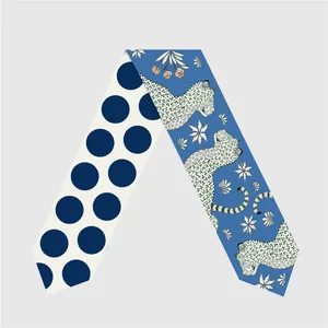 Close-up of dual-sided twilly scarf featuring navy polka dots and leopard floral prints