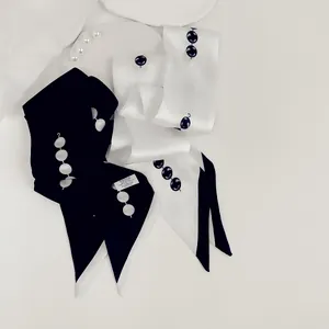 Detail van een elegante gebroken witte zijden sjaal met parel- en knoopversiering