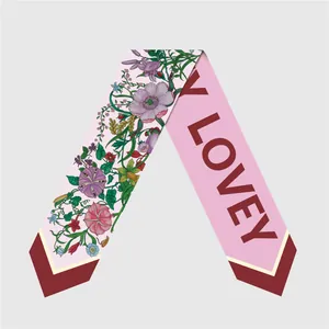 Detail of pink floral silk twilly scarf with LOVEY text and dark red pointed ends
