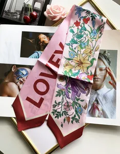 Close-up of pink silk scarf with floral patterns and LOVE lettering on a magazine