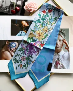 Detailed close-up of a floral print silk twilly scarf with blue borders on magazines
