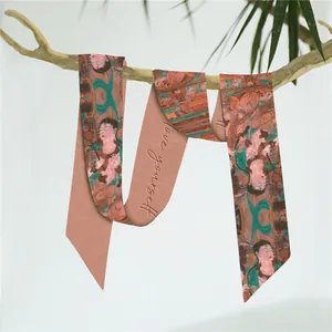 Detail van groene zijden twilly sjaal met vintage print hangend aan een takje