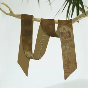 Detail van een smalle zijden sjaal met retropatronen en Love Yourself belettering