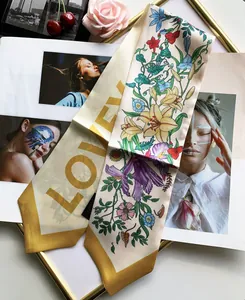 Detailed view of floral silk scarf with LOVEN lettering on aesthetic magazine props