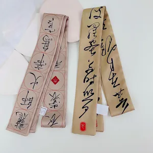 Detailopname van beige zijden twilly sjaals met artistieke zwarte kalligrafieprints
