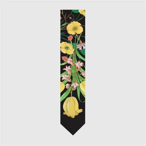 Detailed view of long silk scarf with yellow poppy and pink lily floral print on black fabric