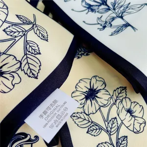 Macro detail van polyester zijden sjaal met blauwe bloemenprint en waslabel erop