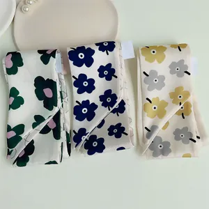 Detailweergave van drie smalle zijden sjaals met bloemenprint en waslabels op een tafel