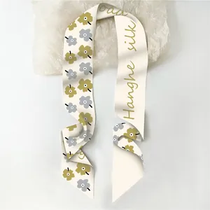Detailweergave van de crème twilly sjaal met gele bloemen en Hanghe silk inscriptie