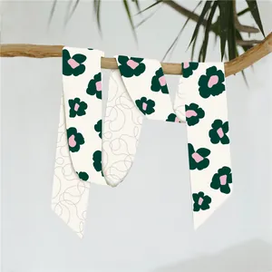 Detail van een zijden sjaal met bloemmotieven hangend aan een tak, natuurlijke esthetiek