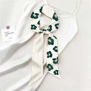 Detail van een groene zijden sjaal met bloemen geknoopt op een witte satijnen jurk