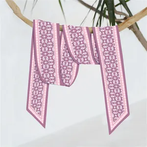 Detailopname van een zijden paisley sjaal die elegant over een natuurlijke boomtak hangt
