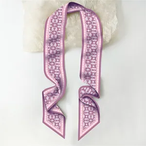 Detailopname van een paarse Twilly-sjaal met paisley-patroon en lichte zijden textuur