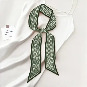 Detail van een donkergroene zijden sjaal met paisley-motief op een witte zijden jurk