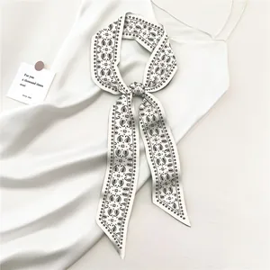 Detail van zijden smalle sjaal met zwart paisley patroon op een witte satijnen jurk