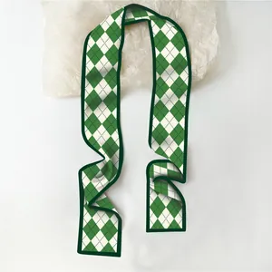 Detail van zijden smalle sjaal met groen en wit ruitpatroon op een witte achtergrond