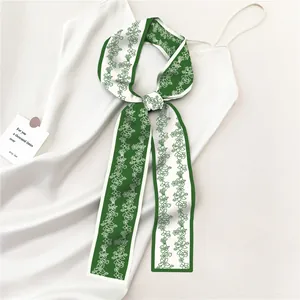 Detail van een groene zijden twilly sjaal met bloemen geknoopt op een witte jurk