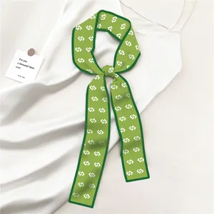 Detail van groene zijden sjaal met witte geometrische patronen en afgewerkte randen