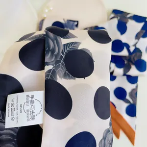 Detail van zijdezachte sjaalstof met donkerblauwe stippen en grijze rozenpatronen