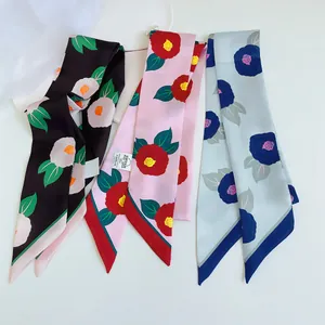 Detail van smalle zijden sjaals met camellapatronen in zwart, roze en blauwe tinten