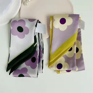Gedetailleerd bovenaanzicht van bloemen zijden twilly sjaals met madeliefjes en labels