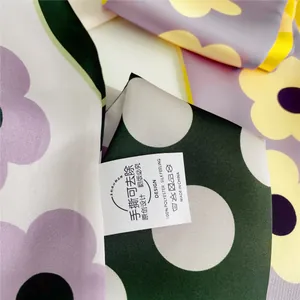 Detail van zijden sjaal met paarse bloemenprint, groene stippen en gele rolzoomranden