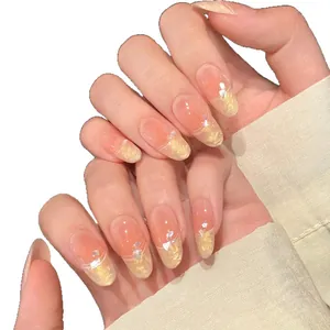 Faux ongles amande nude style français avec nacre, dégradé doré et perles
