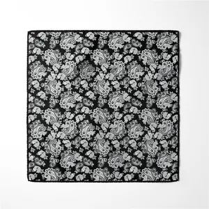 Detailed view of square silk scarf featuring white paisley patterns on black background