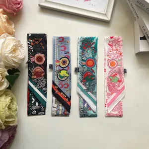 Detail of four floral and equestrian patterned twilly scarves neatly arranged on a white desk
