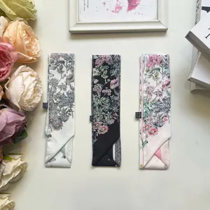 Dettaglio di foulard in seta twill a fiori con trama in poliestere ed etichette di lavaggio