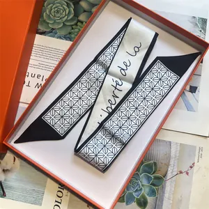 Detail of black and white silk skinny scarf with star pattern and orange gift box